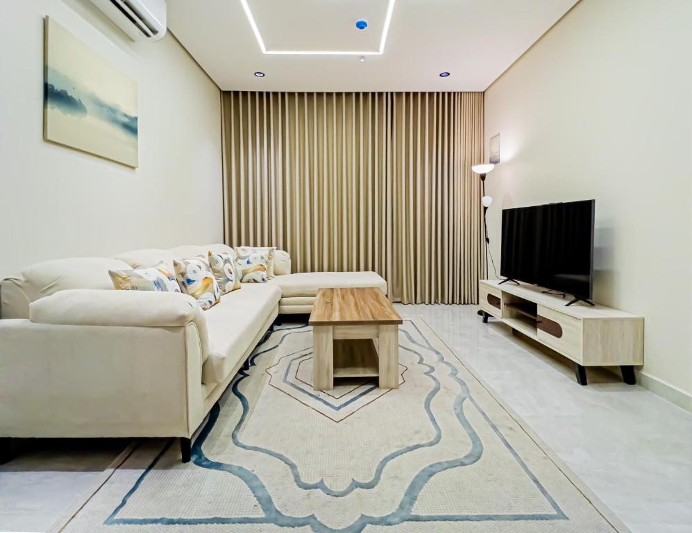 een woonkamer met een bank en een tv bij Comfy apartment in AlKhobar in Al Khobar
