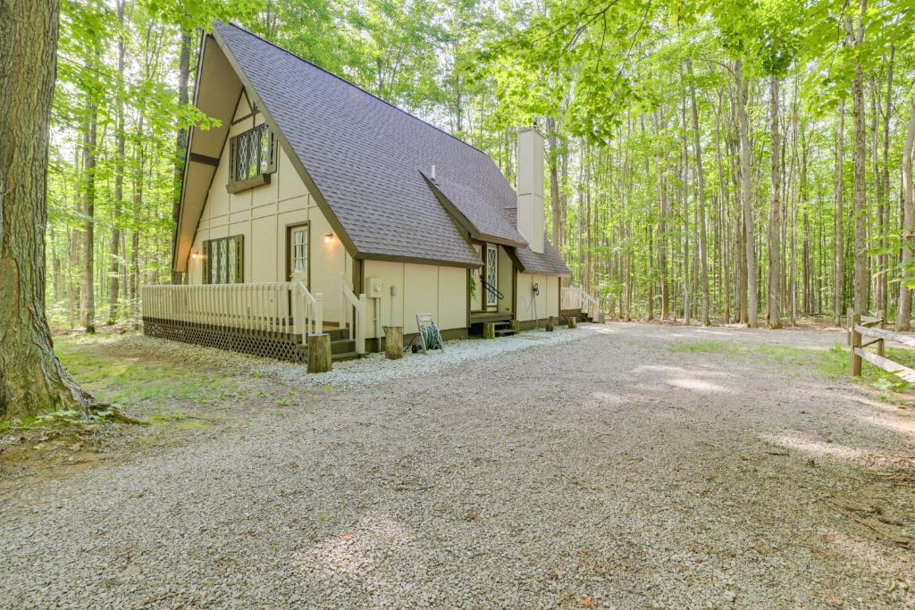 ein Haus mit einer Kiesauffahrt im Wald in der Unterkunft Woodsy A-Frame Cabin with Lakes of the North Access in Mancelona