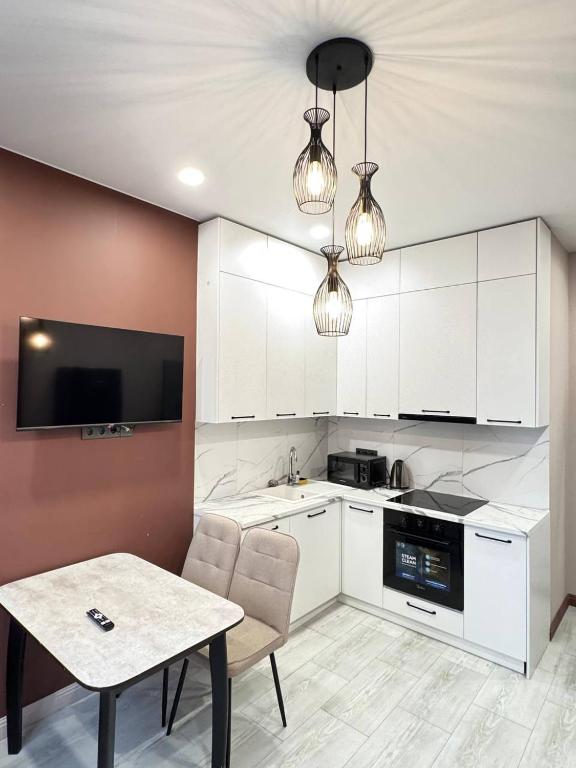 a kitchen with white cabinets and a table with chairs at 2 room in the very center of the city near the mega park and walking distance to the Arbat in Almaty