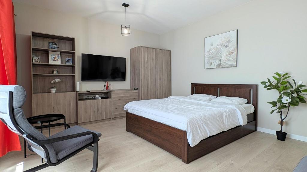 a bedroom with a bed and a chair and a television at Ursus Pleasant Apartment by BookingHost in Warsaw