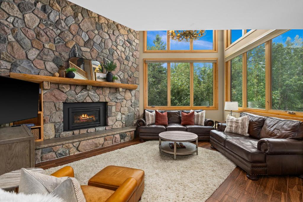 sala de estar con chimenea de piedra y muebles de cuero en Gorgeous Executive Lutsen Townhome - Ski-in Ski-out, Pool, Hot Tub, Hiking, Biking, campfires and more!, en Lutsen