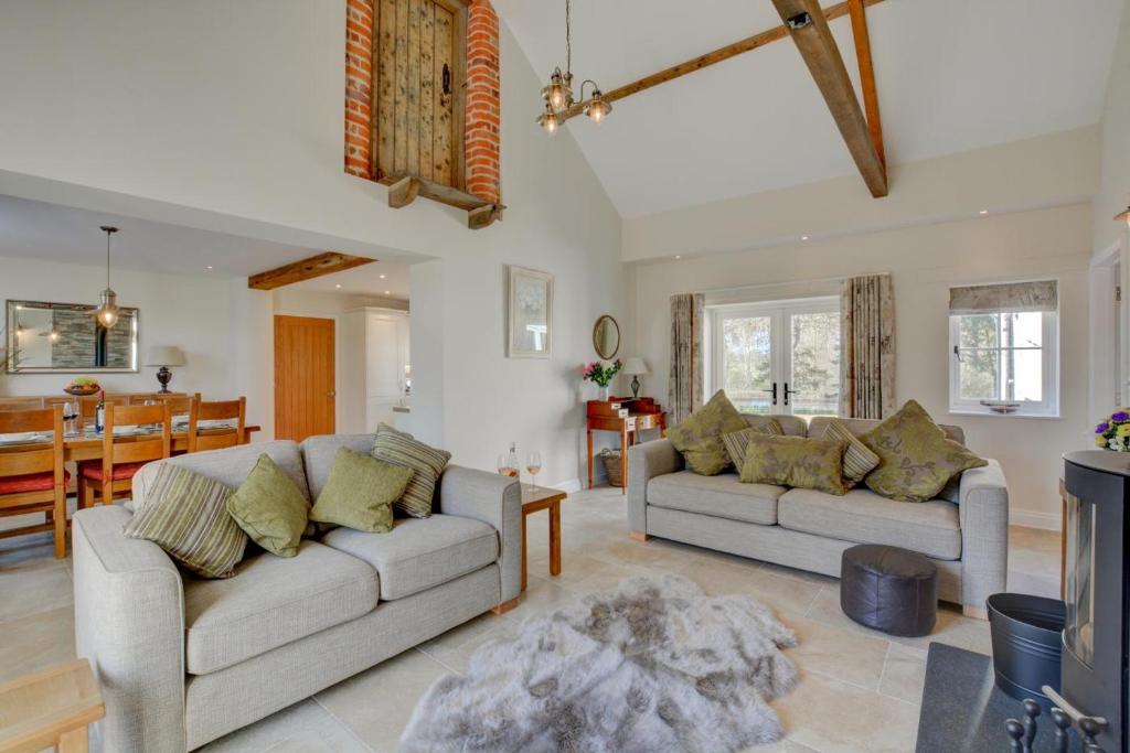 een woonkamer met 2 banken en een eetkamer bij Mill Cottage in Elsing
