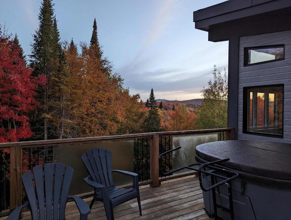 a balcony with two chairs and a table on a deck at Maison contemporaine Tremblant- Spa & tranquillité in Lac-Superieur