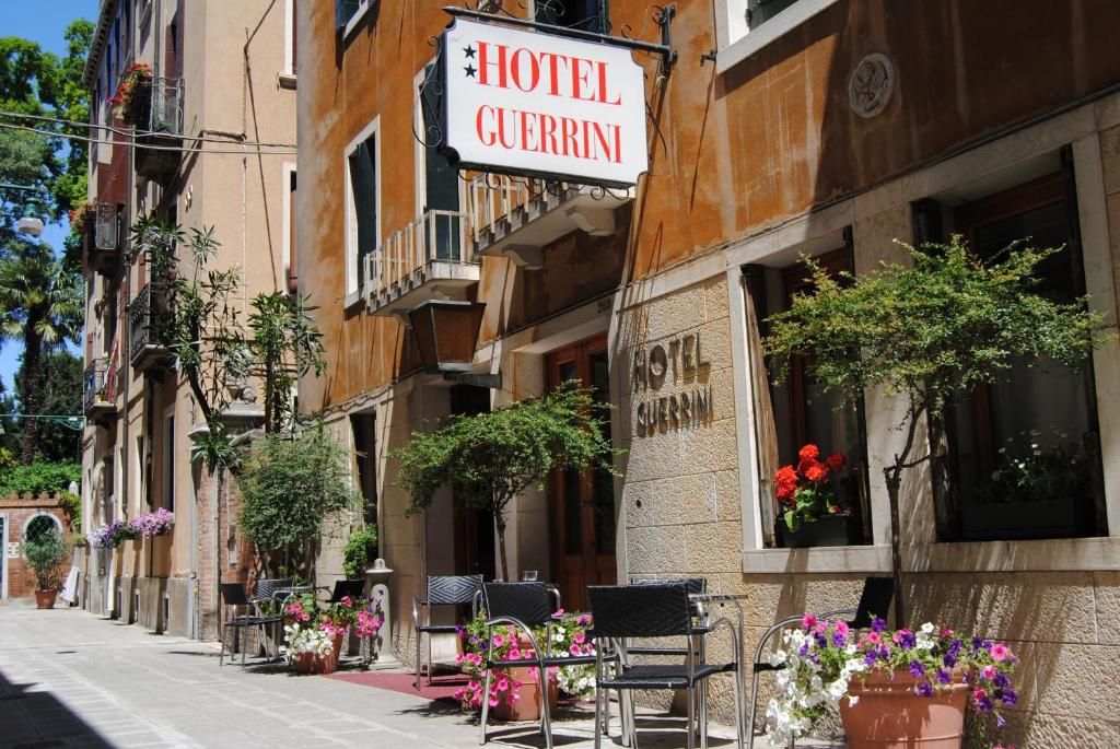 una calle con mesas, sillas y flores en un edificio en Hotel Guerrini, en Venecia