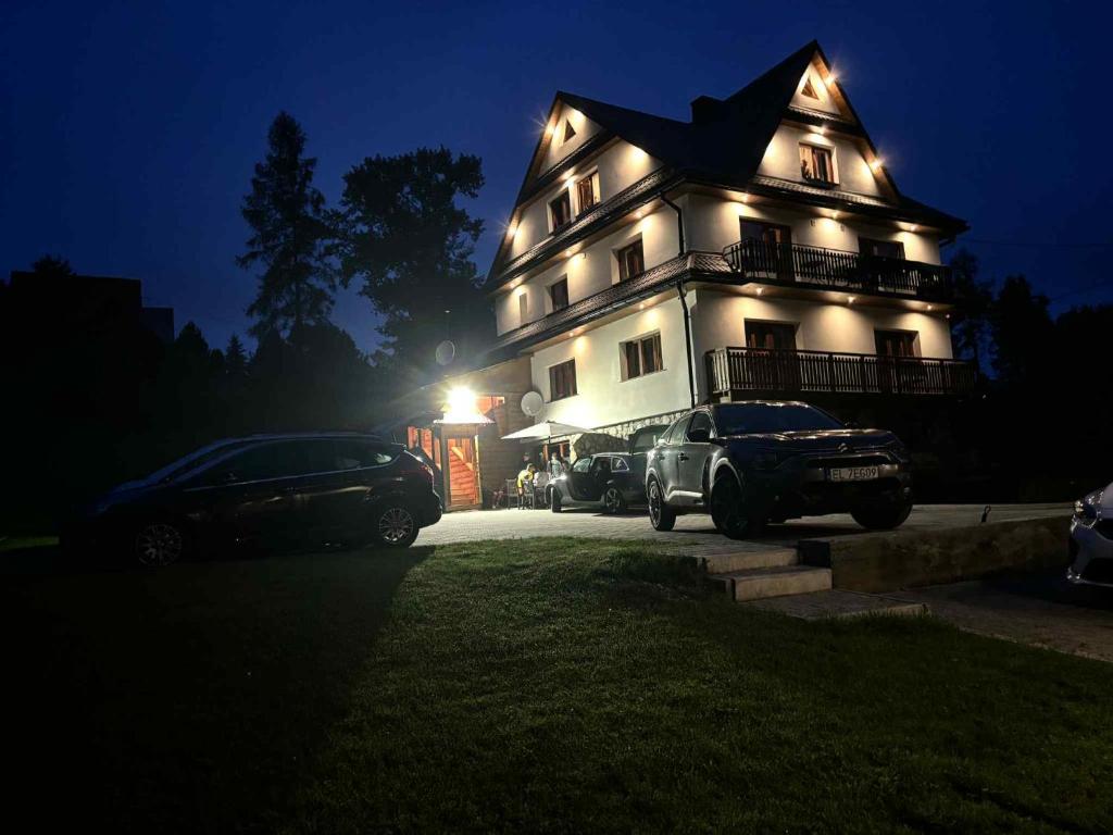 a large house with cars parked in front of it at night at U Parów - pokoje z jacuzzi i sauna, Białka Tatrzańska in Białka Tatrzańska