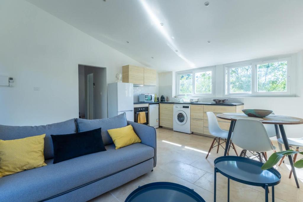 Una sala de estar con un sofá azul y una cocina. en Le Mozart - Aix, en Aix-en-Provence