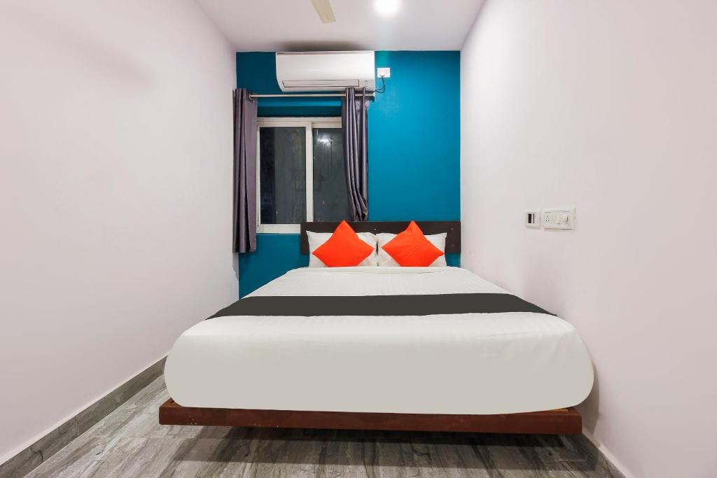 a bedroom with a bed with orange pillows at Capital O Che Sigma Hotel in Hyderabad