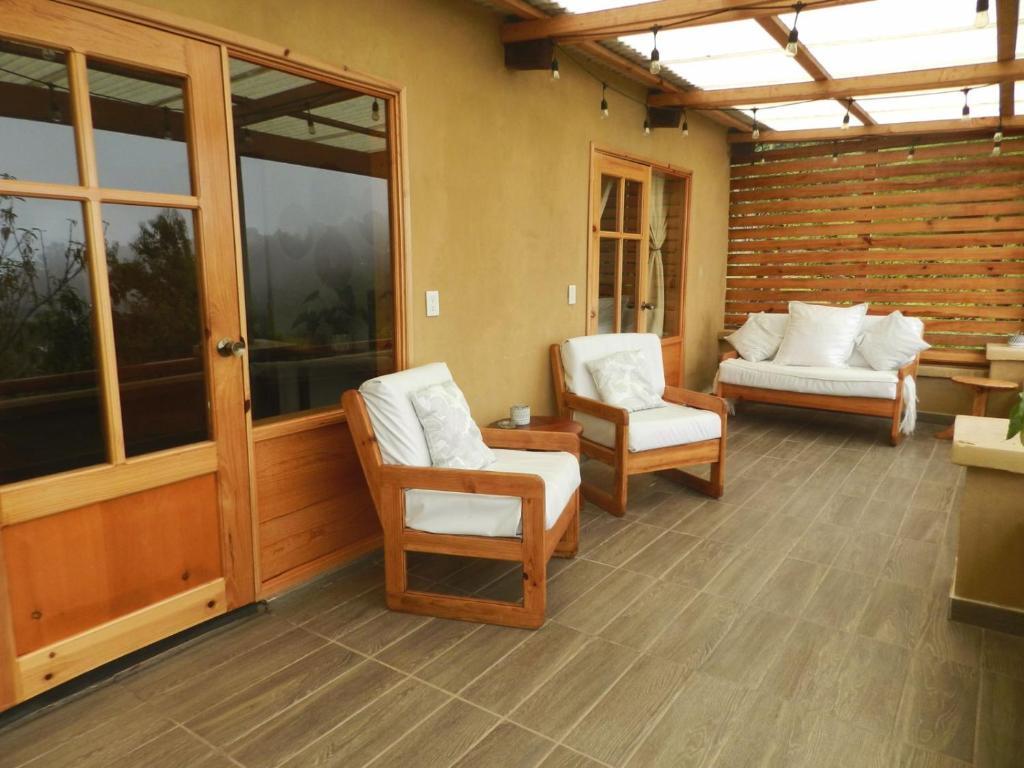 a screened in porch with two chairs and a couch at Casita Ikal in Cedro