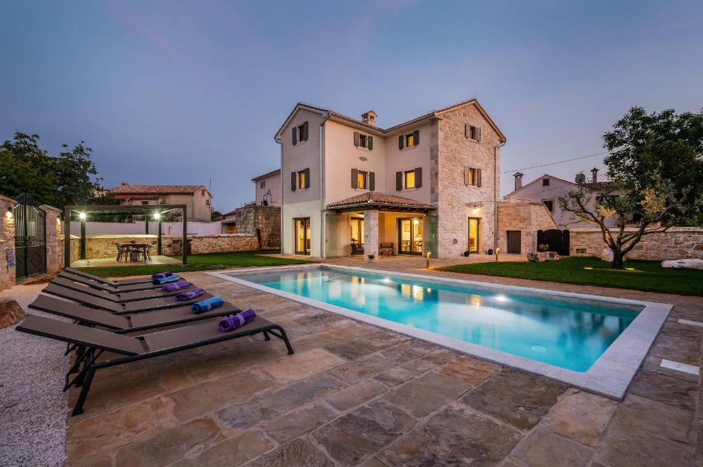 a house with a swimming pool in front of a house at Villa Cangarela in Višnjan
