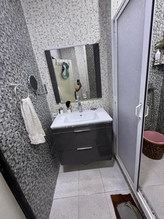a bathroom with a sink and a shower and a mirror at Comfortable apartment in Tangier