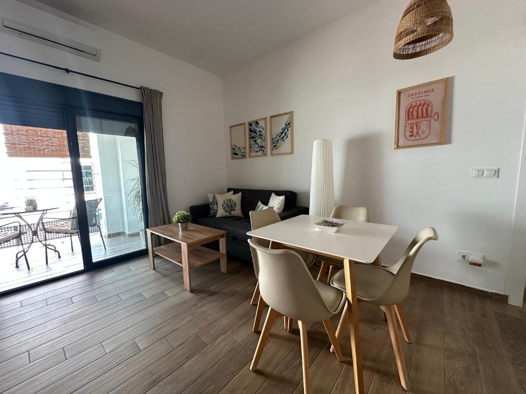 a living room with a table and chairs and a couch at Apartamentos Matilda Conil - Playa in Conil de la Frontera