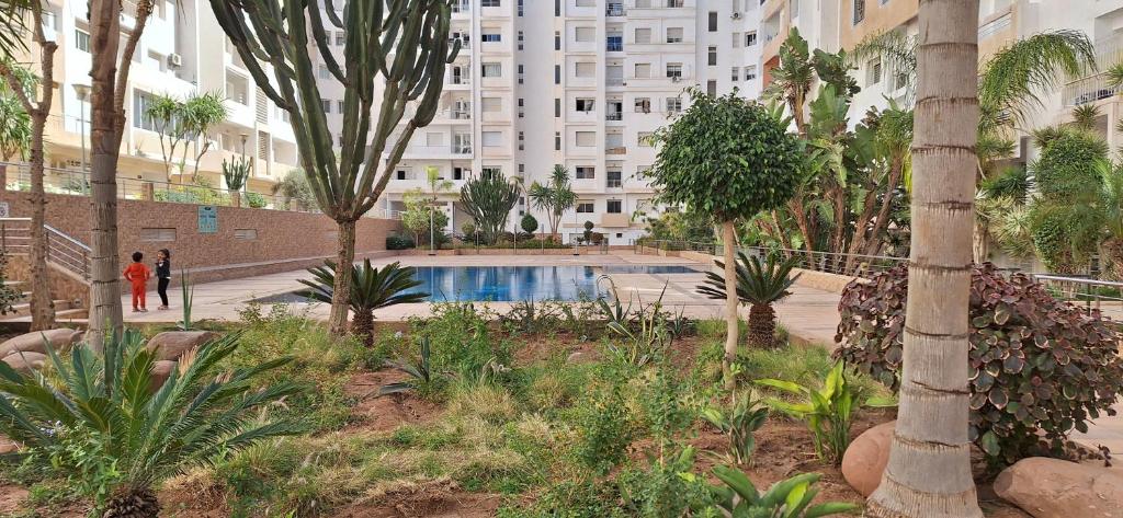 um pátio com piscina num edifício com palmeiras em Agadir - Appartement vue mer et montagne em Agadir