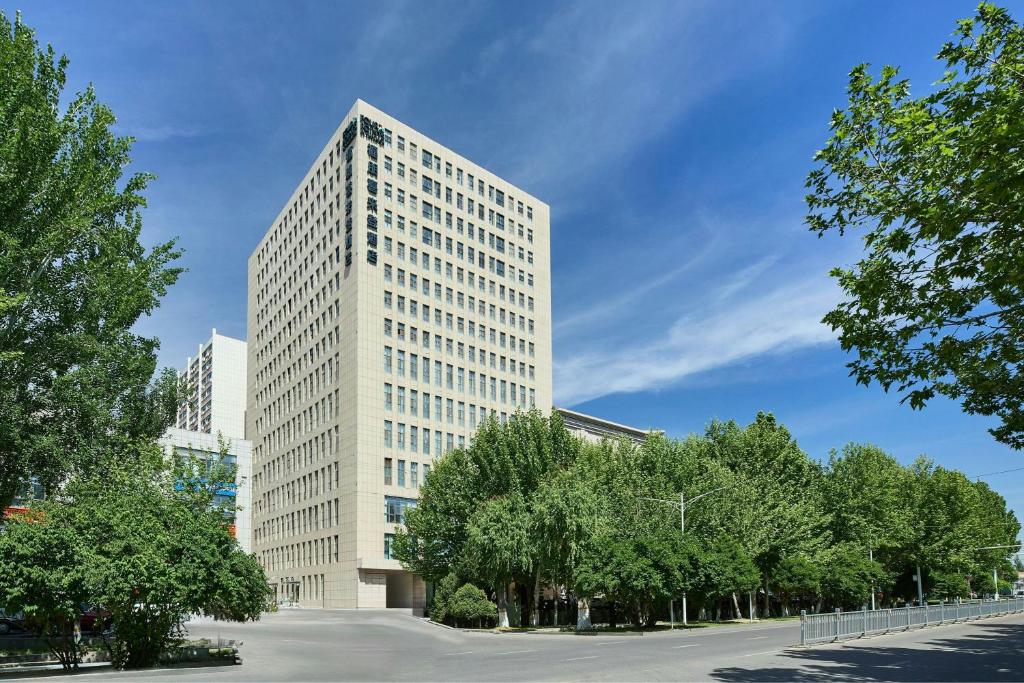 a tall white building with trees in front of it at Four Points by Sheraton Yining in Yining