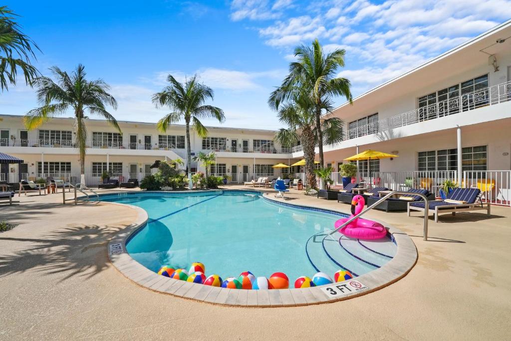 a swimming pool with beach balls in front of a building at Tradewinds Apartment Hotel Miami Beach in Miami Beach