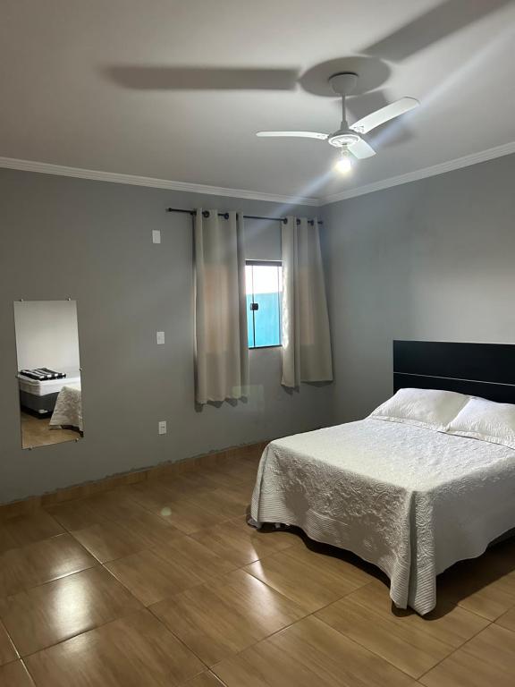 a white bedroom with a bed and a window at Pousada A Serra Mistica in São Thomé das Letras