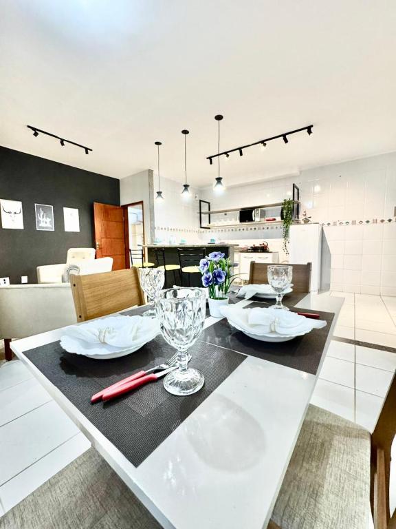 a dining table with two plates and glasses on it at APARTAMENTO CONFORT NO CENTRO Ar cond 2 QUARTOS in Formosa