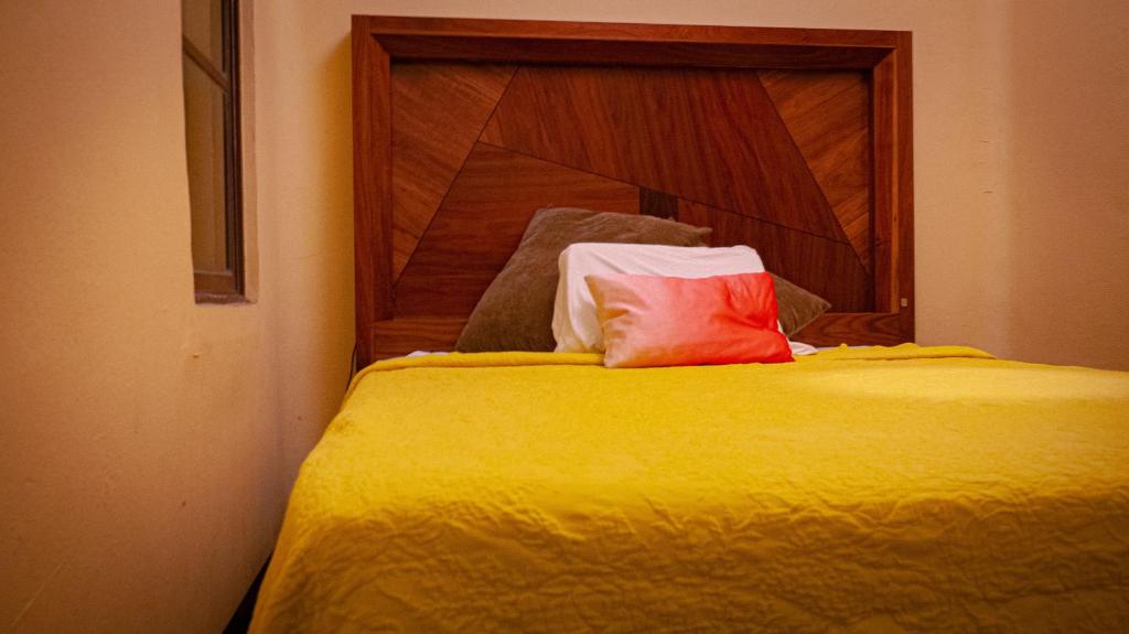 a bed with a red pillow on top of it at céntrico guadalajara in Guadalajara