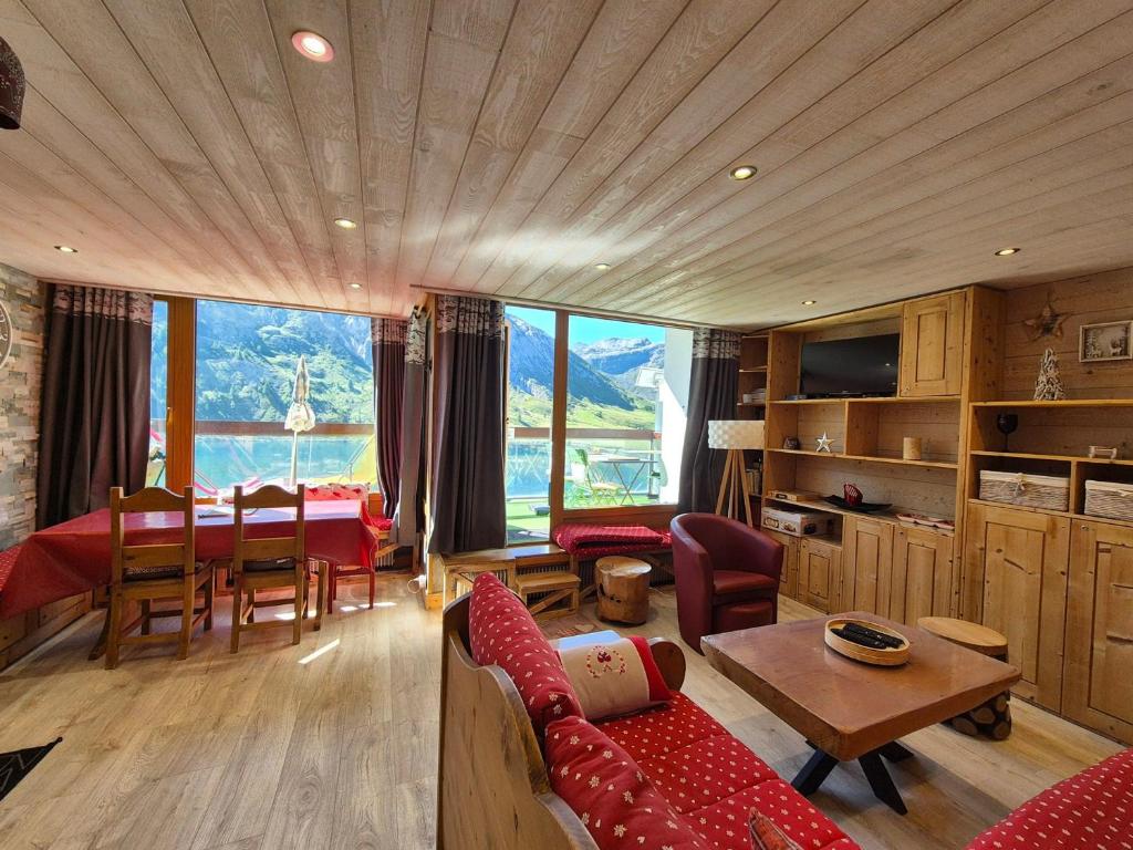 a living room with a red couch and a table at Appartement rénové proche des pistes avec balcon - FR-1-502-389 in Tignes