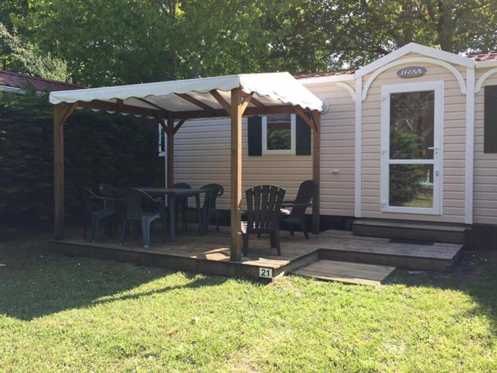 une maison avec une table et des chaises sur une terrasse dans l'établissement Mobil-home 30m² avec terrasse à Vendays-Montalivet - API-1-52-794, à Vendays-Montalivet