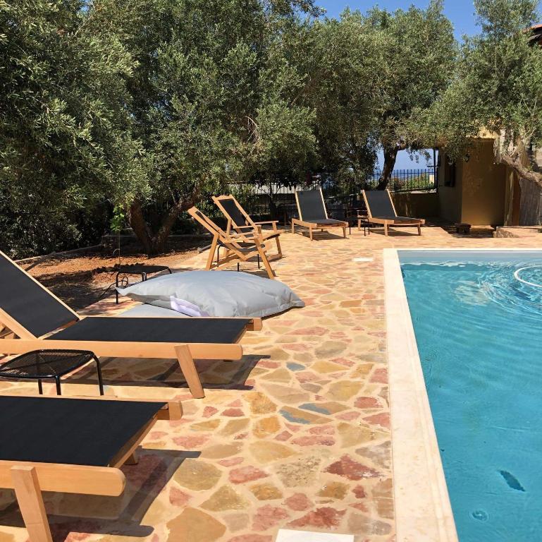 a swimming pool with lounge chairs next to a swimming pool at Wunderschönes Ferienhaus In Agios Stefanos in Foútia