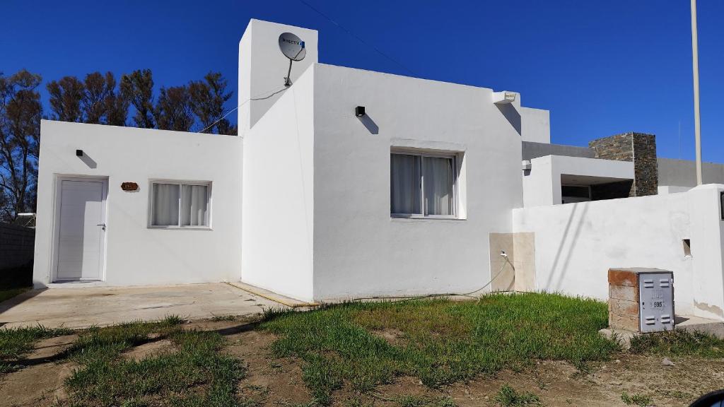 a white house with a door and a yard at Alquiler Temporario Oliva in Oliva