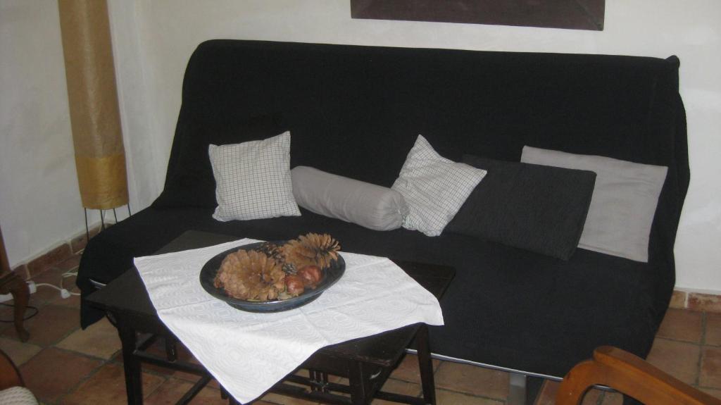 a black couch with pillows and a bowl of fruit on a table at Al Sil Ram in Alfacar