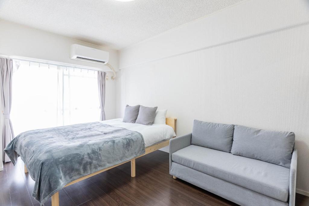 un dormitorio con una cama y un sofá en Uburu Apartment, en Fukuoka