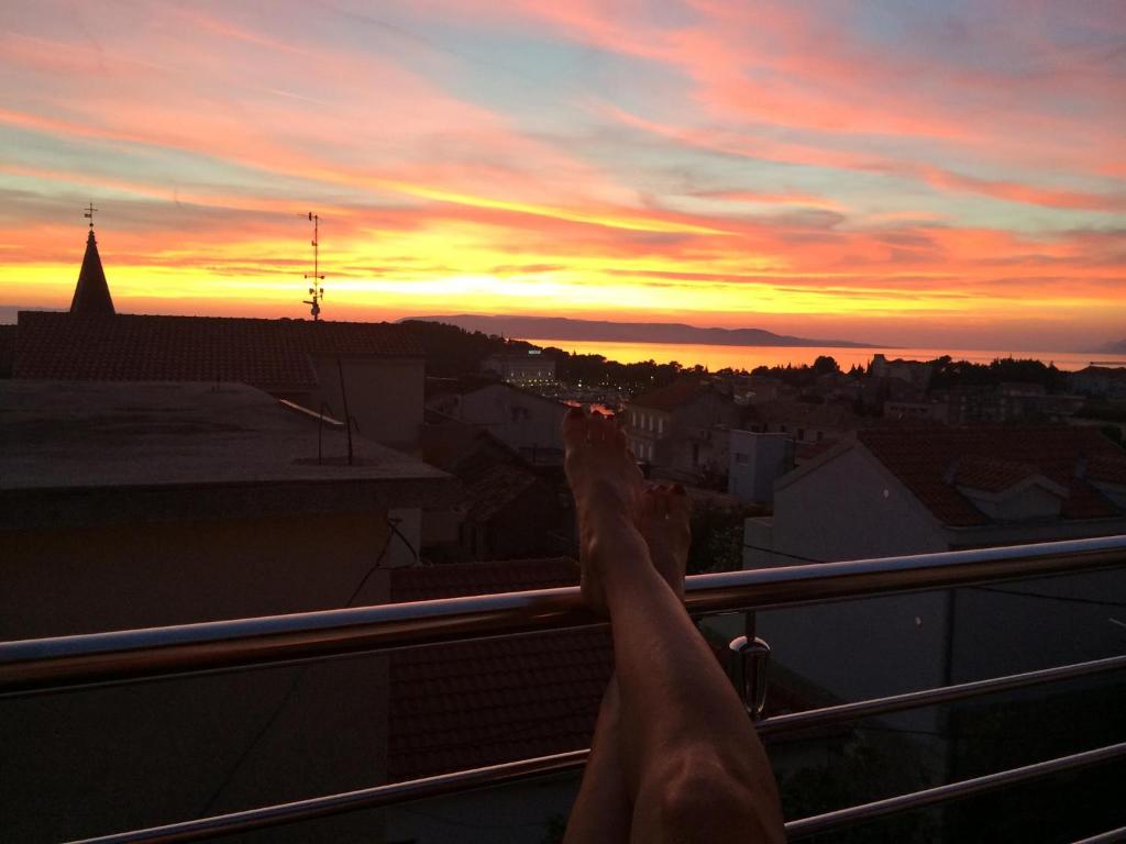 a person standing on a balcony watching the sunset at Luxury penthouse with sea view in Makarska