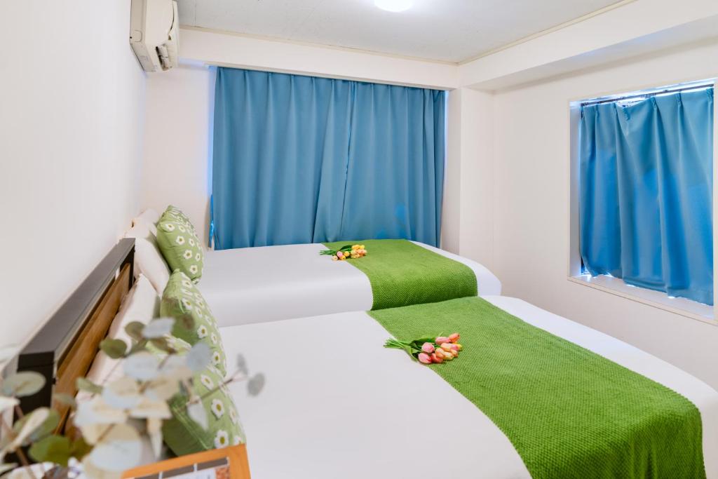 two beds in a room with blue curtains at 2 bedrooms and 1 living room on the 1st floor, 40sqm house, 10 min walk to Oji 2 min walk to Kajiyara Toden Arakawa Line in Wada