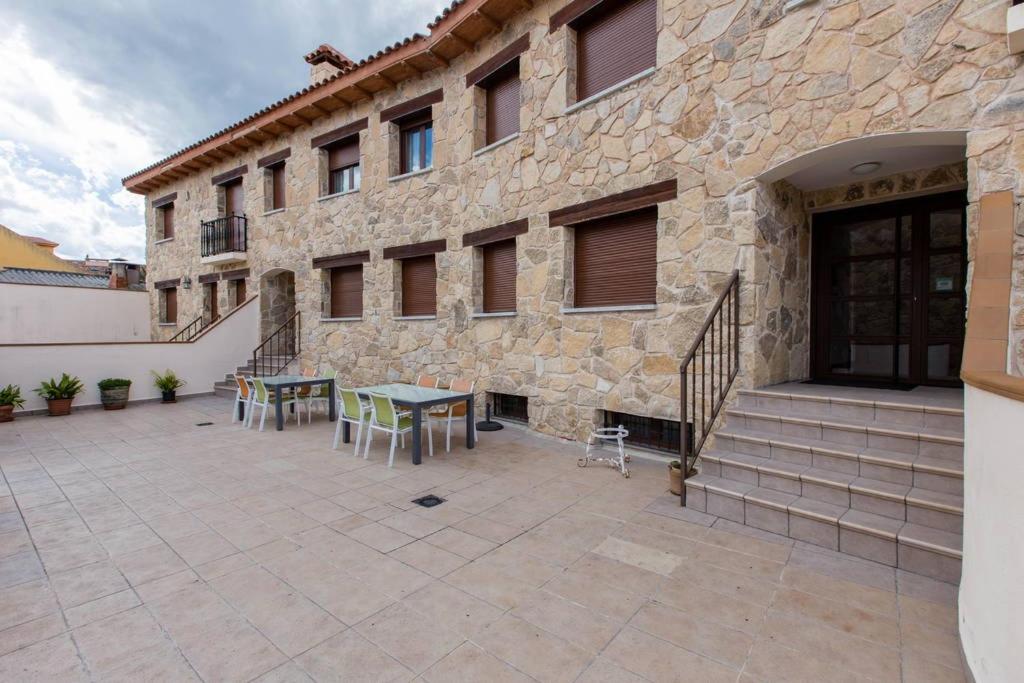 un edificio de piedra con un patio con mesa y sillas en Alojamientos Botica Rural, en La Cabrera