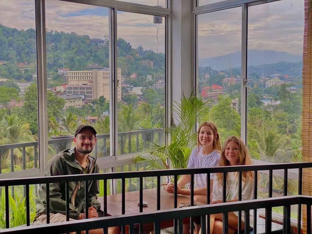a group of people sitting on a balcony with a view at The Kandy Home & City mirror Hostel in Kandy