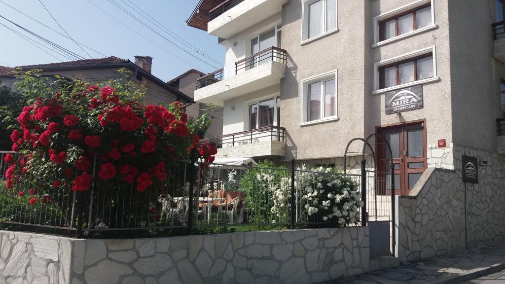 un bâtiment avec des fleurs rouges sur une clôture dans l'établissement Mira Guest House, à Dobrinichte