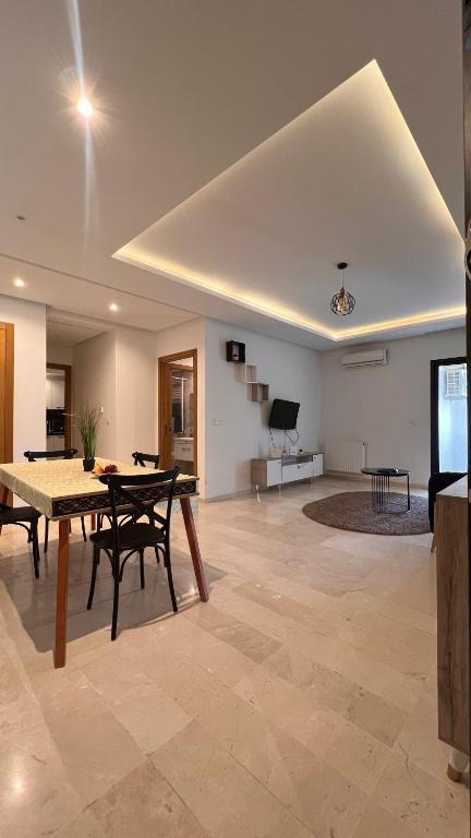 Una sala de estar con una mesa y sillas y un televisor. en Terrazzino de Fatimides, en Túnez