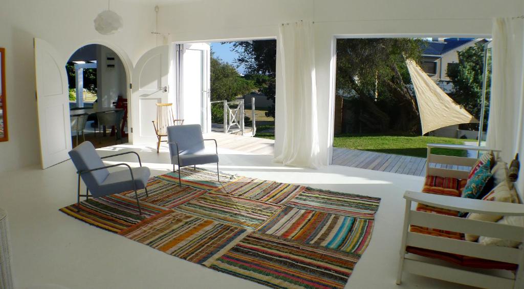 a living room with two chairs and a rug at Pashasha Beach House in Hermanus