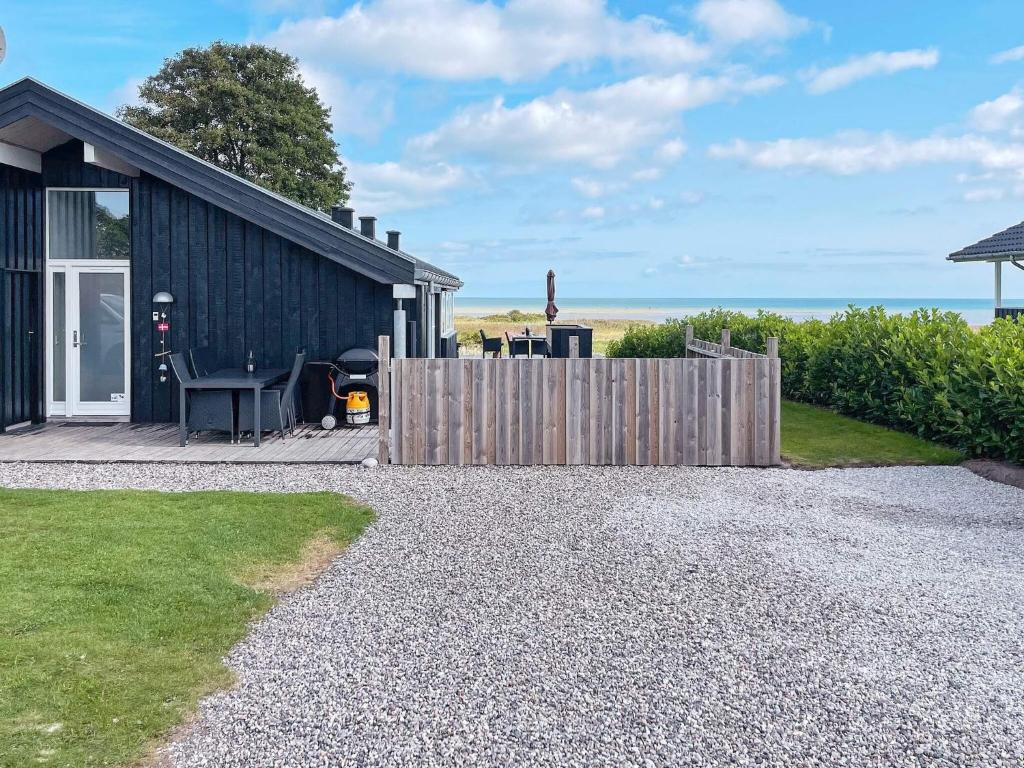 a small black cottage with a wooden fence and the ocean at Modern Beach House - By Traum Ferienwohnungen in Haslevgårde