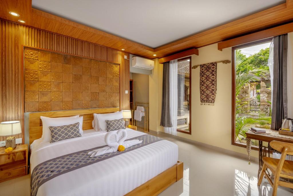 a bedroom with a large bed and a desk at Poset Unique Inn in Ubud