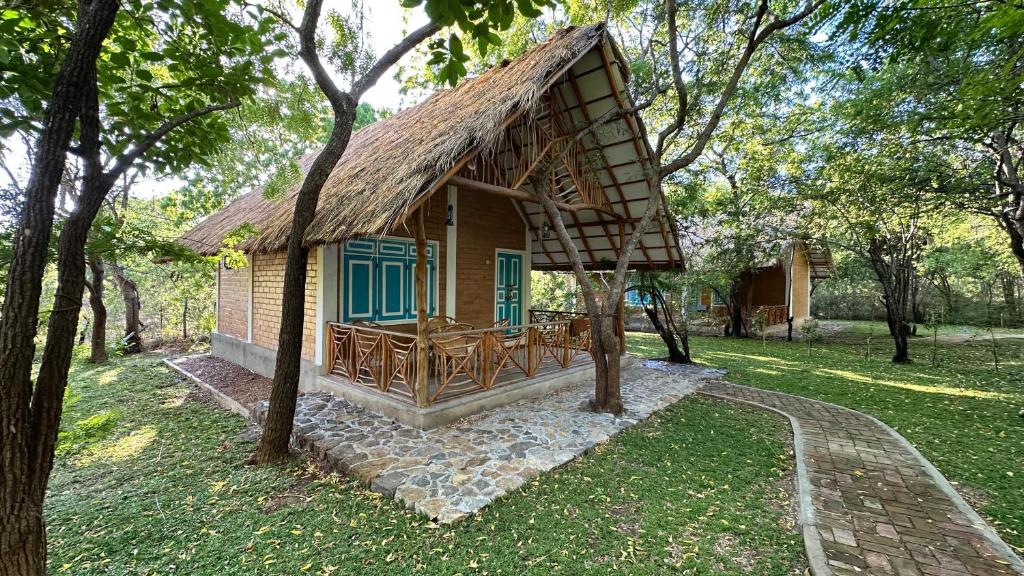 mały domek z dachem krytym strzechą w trawie w obiekcie Lake Forest Holiday Resort w mieście Kataragama