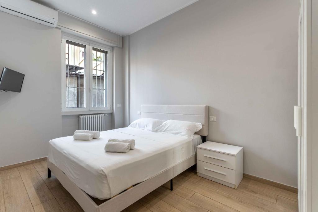 a white bedroom with a bed and a window at MI Michetti 20 in Milan