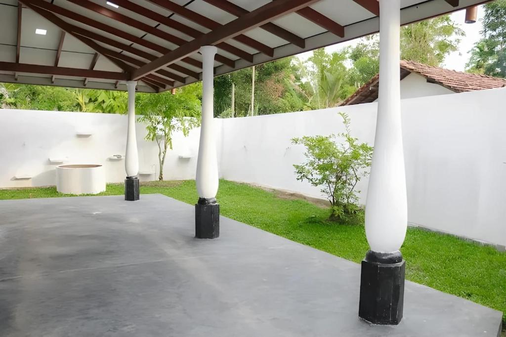 a white building with white columns and a yard at Malmika Villa in Ahangama