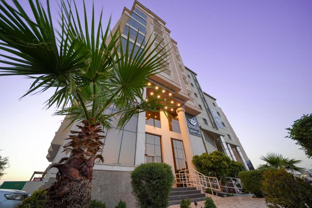 a building with a palm tree in front of it at Seven Palaces Hotel in Hafr Al Baten