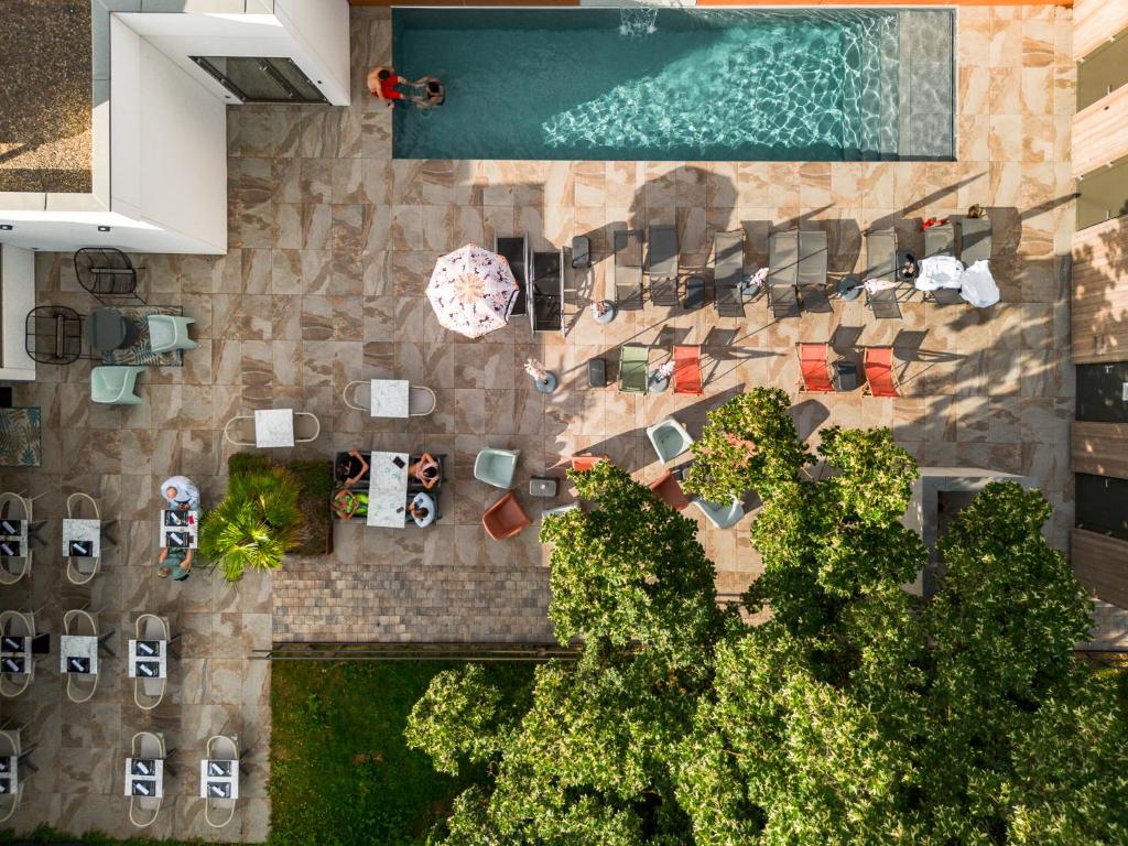 an overhead view of a swimming pool with chairs and a garden at Brit Hotel, Spa & Restaurant - Colmar Est in Bischwihr