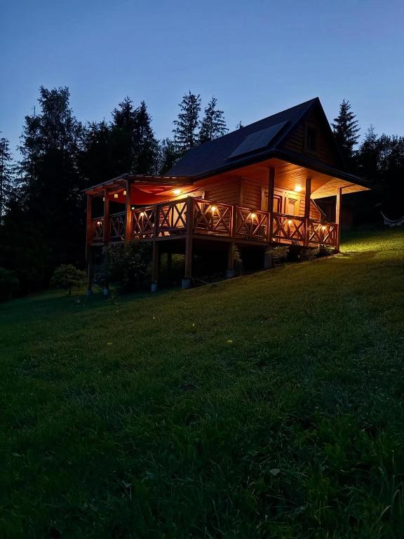 a large wooden cabin with lights in a field at Domek w Górach Prywatna Sauna i Balia in Klikuszowa