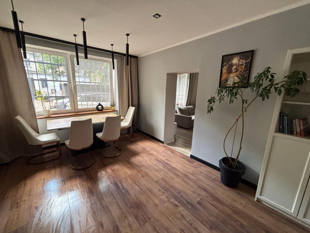 Una sala de estar con una mesa y sillas y una ventana. en KK Apartament Piekarska Oficyna, en Bytom
