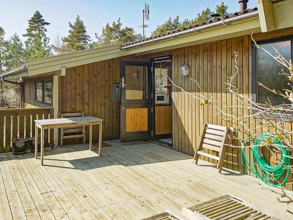 a wooden house with a table and a bench on a deck at 6 person holiday home in Nexø in Vester Sømarken