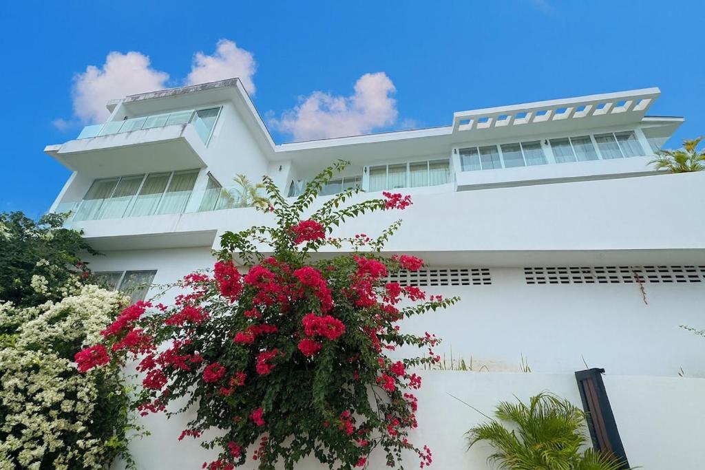 ein weißes Gebäude mit einem hängenden Korb voller roter Blumen in der Unterkunft Bobut beach, Koh Samui, Thailand, half mountain sea view, four-bedroom, four-bathroom villa B in Chaweng