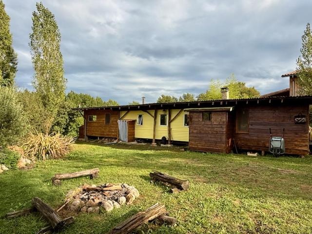 una casa e un fienile con un cortile con tronchi di Small house, charming cabin, Cozy place a Montbrun-Bocage