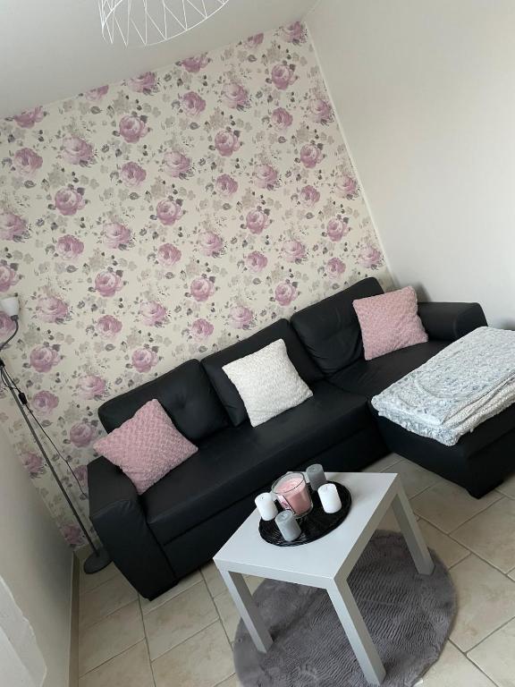 a living room with a black couch and a table at Maison chaleureuse proche du circuit des 24h et autoroute in Écommoy