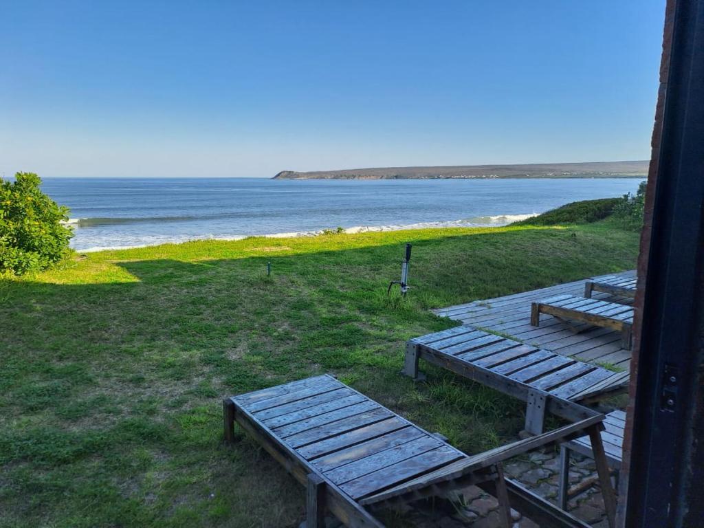 zwei Holzbänke auf einem Strand in der Unterkunft Tokkelos - Beach front Bungalow in Witsand