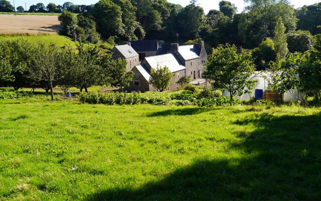 a field of green grass with houses and trees at Gîte Ar Boutilh in Ploulech