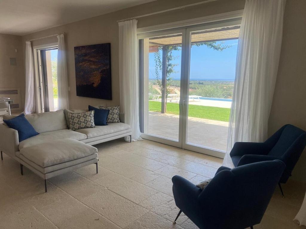 a living room with a couch and chairs and a sliding glass door at Villa Heron Sicily in Noto